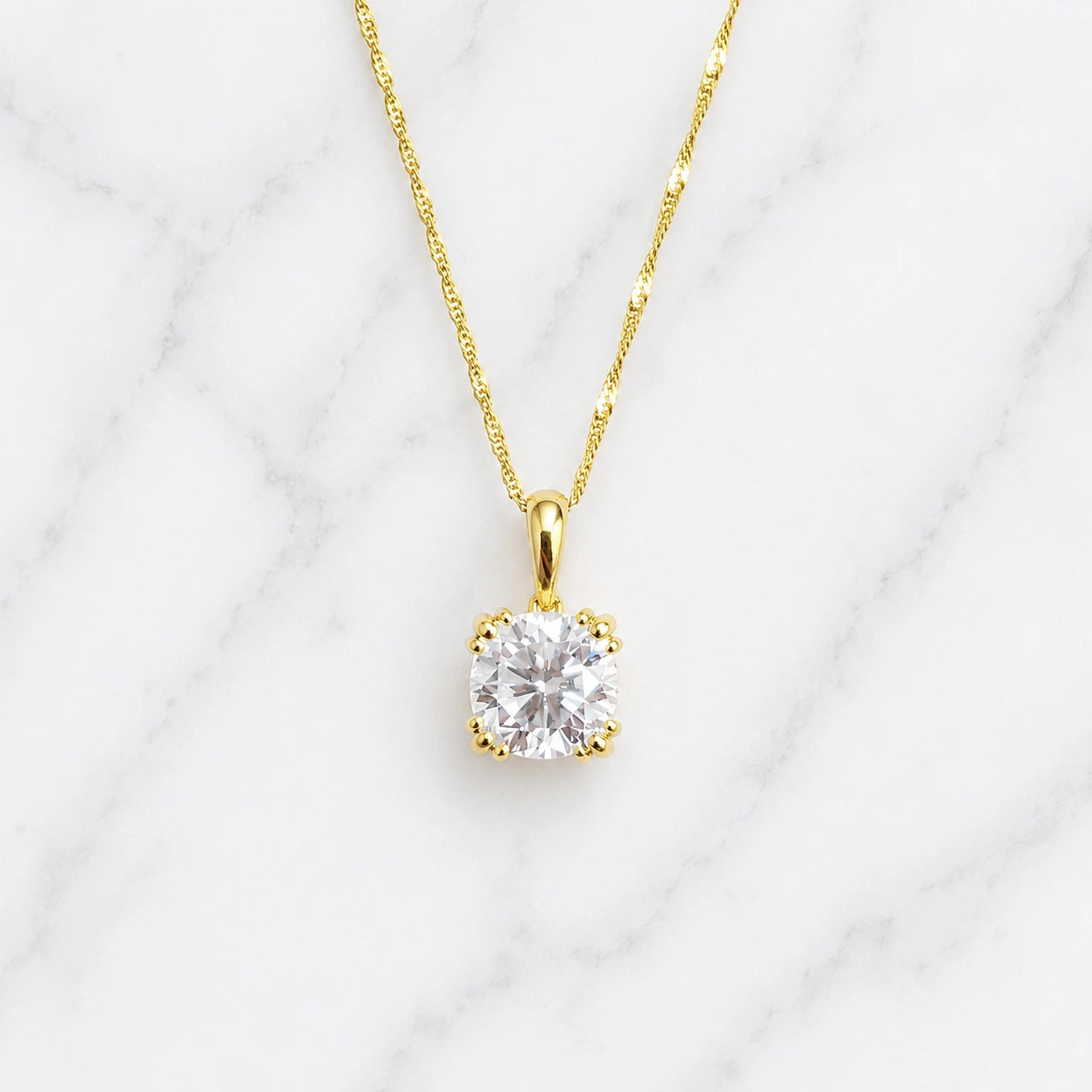 3 ct cushion cut moissanite solitaire pendant necklace in 18k yellow gold on white marble background