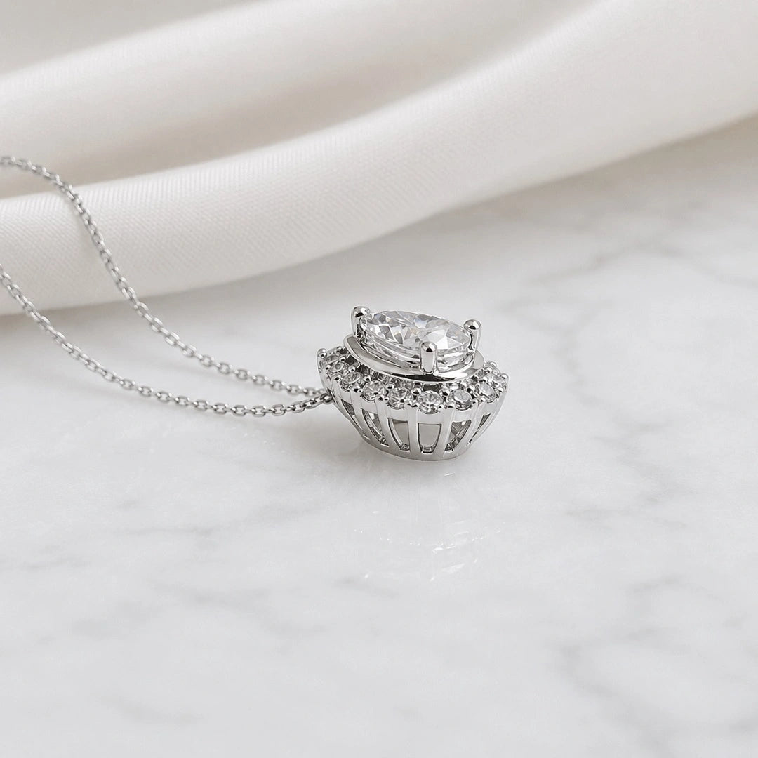 Side angle profile view of pear cut moissanite halo pendant showing setting depth